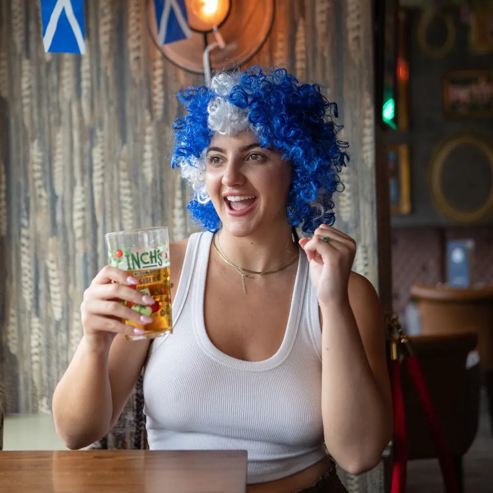 Scotland supporter wearing a blue and white afro wig during match day celebrations